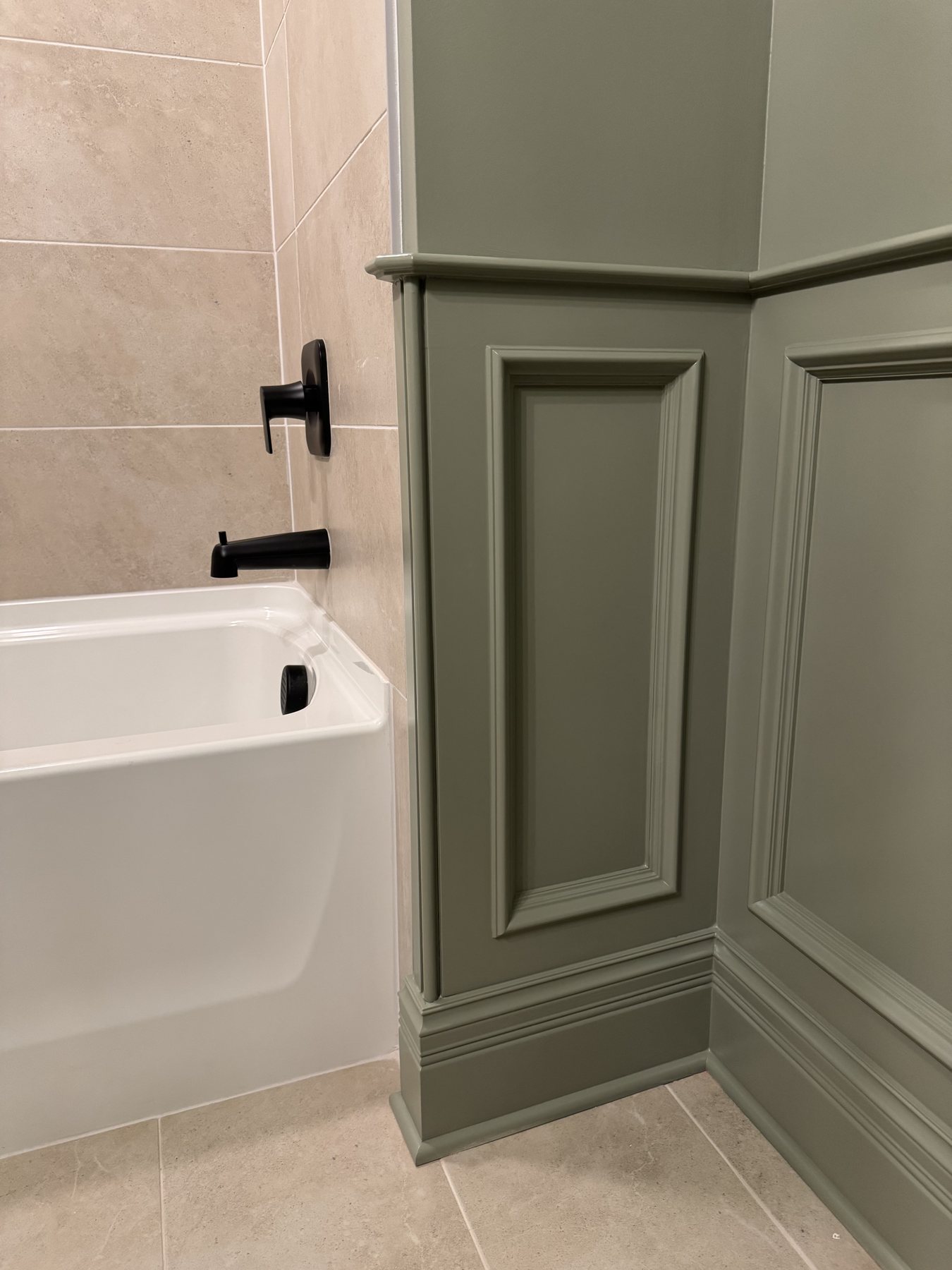 Recessed-panel wainscoting returned cleanly where it meets a tiled tub surround
